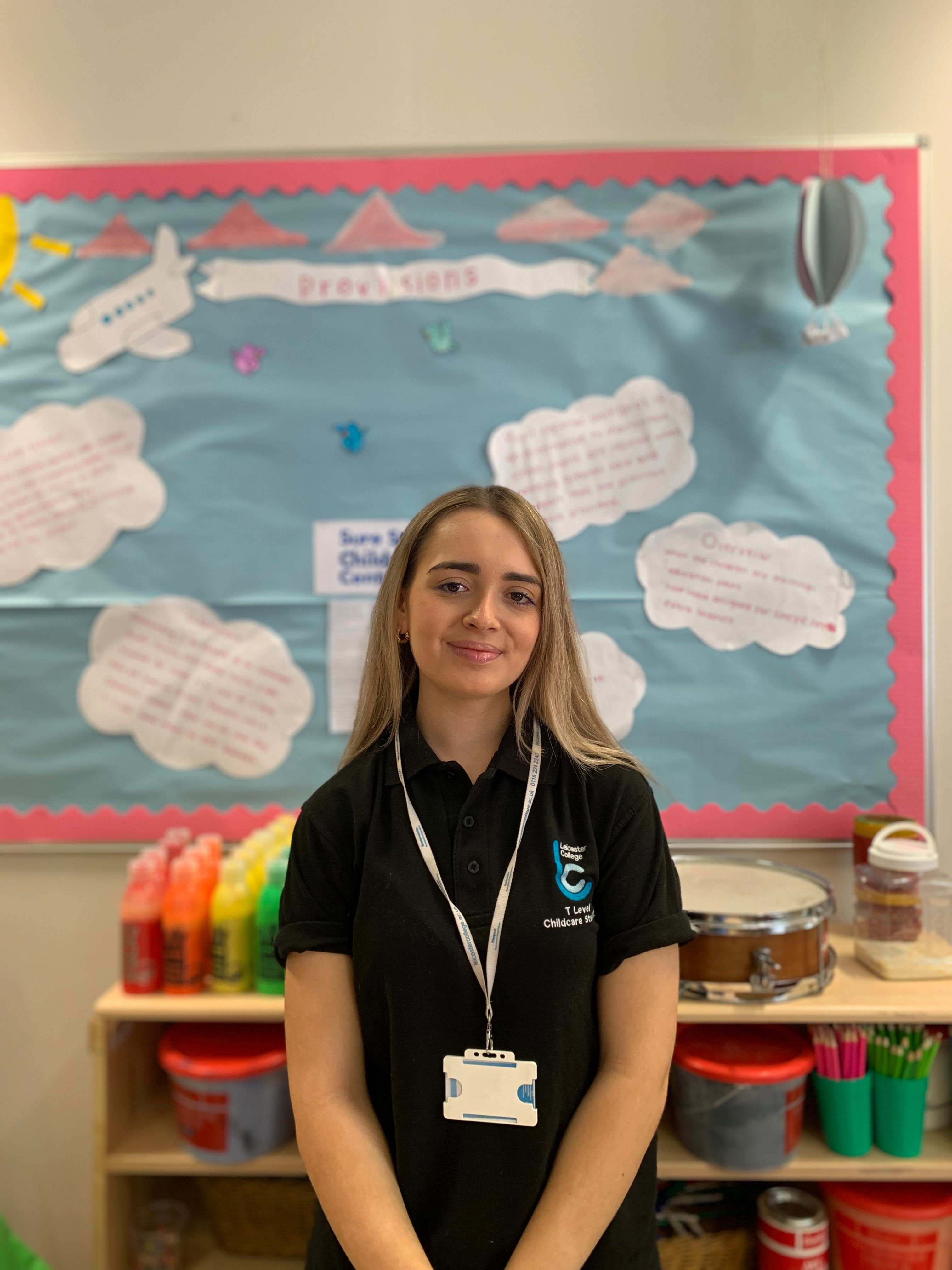 Sourianna standing in the mock nursery, she is wearing the childcare Leicester College uniform.