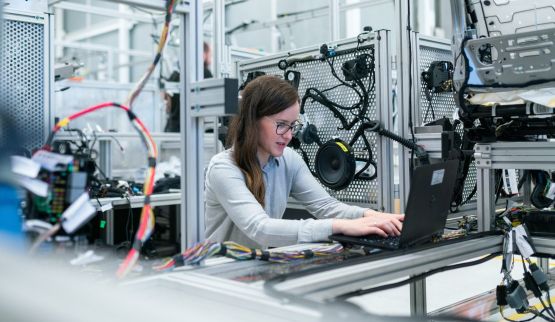 White female student sitting at laptop in engineering building