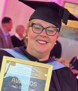 Katy Herrod with award certificate wearing a mortarboard