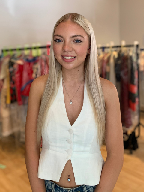 student wearing a white waistcoat standing in front of a fashion rail