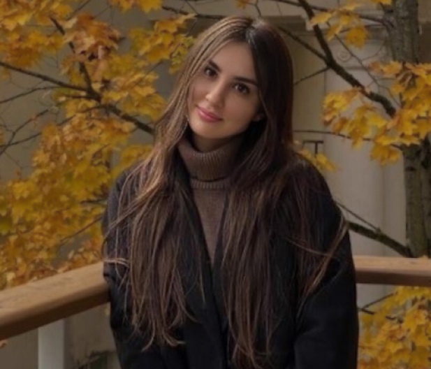 young girl with long hair posing behind autumn trees